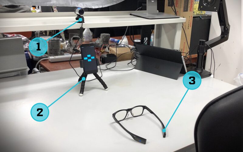Experimental setup with a camera, a smartphone running the study application and a pair of JINS MEME smart glasses