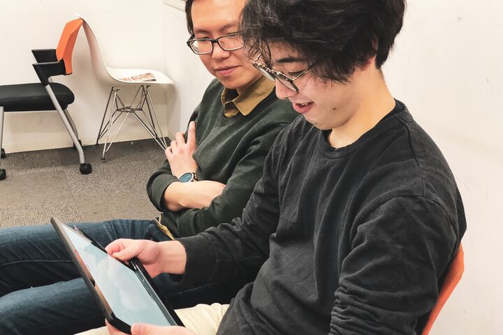 Study participant reading on a tablet while an observer looks over the shoulder